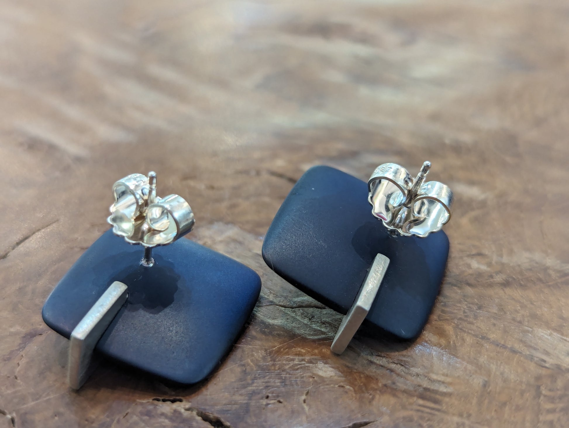 Two square navy blue earrings with silver posts. 