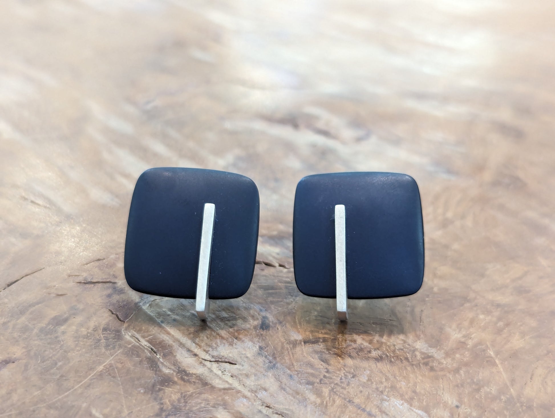 Two navy blue square earrings with a vertical silver line detail 